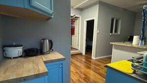 Une cuisine avec des armoires bleues, un plan de travail en bois et une casserole en acier inoxydable.
