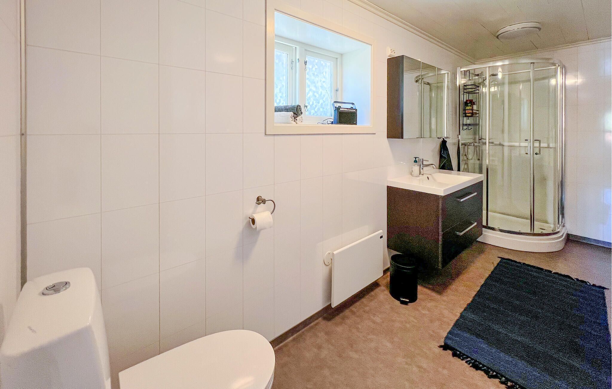 Een badkamer met toilet, wastafel, douche en een douchecabine met glazen wanden.