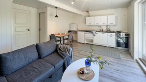 A compact living space with a sofa, a dining table, a kitchen area, and a small workspace. - Stunning apartment in Mandal with house sea view (Mandal)