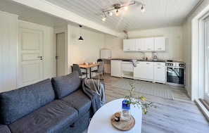 A compact living space with a sofa, a dining table, a kitchen area, and a small workspace. - Stunning apartment in Mandal with house sea view (Mandal)