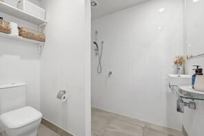 Een moderne badkamer met toilet, douche en een douchecabine met wastafel.