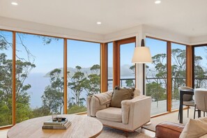 Une chambre moderne dotée d’une grande fenêtre offrant une vue panoramique sur les arbres et l’eau.