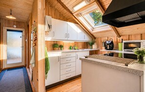 Eine moderne Küche mit weißen Schränken, einer Mikrowelle, einem Wasserkocher und einer Kaffeemaschine.