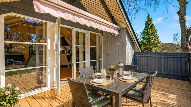 Ein Essbereich im Freien mit einem Tisch für zwei Personen, Korbstühle und einer Holzterrasse.