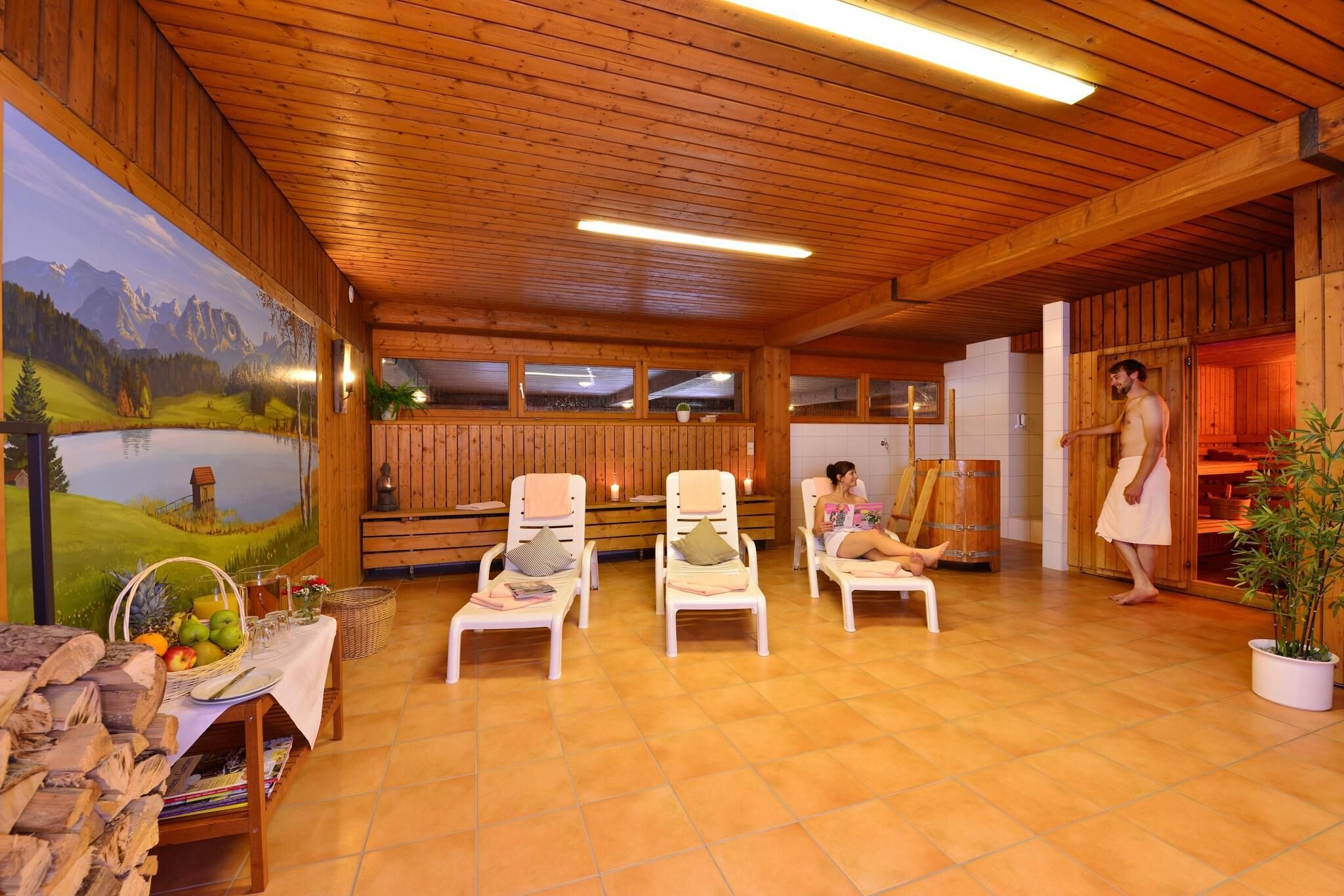 A wooden interior with a mural, seating area, and sauna.