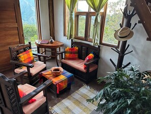 A cozy room with wooden furniture, a round table, and a view of greenery outside.