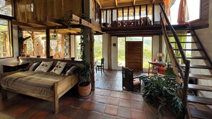 A rustic interior with a loft bed, a wooden staircase, and a large window. - Island in the Sky--Shisa House
Small custom home built with love in Cahuasqui (Cahuasqui)