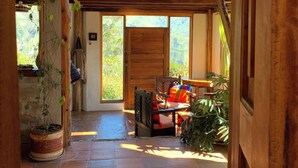 A rustic interior with a wooden staircase, a view of the outdoors, and a seating area with a table. - Island in the Sky--Shisa House
Small custom home built with love in Cahuasqui (Cahuasqui)