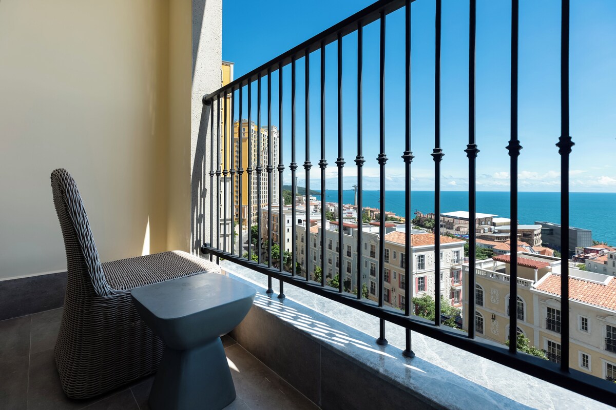 A balcony with a view of the sea and buildings.