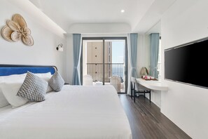 Ein Hotelzimmer mit einem großen Bett, einem Schreibtisch mit Stuhl, einem Fernseher und einem Balkon mit Aussicht.