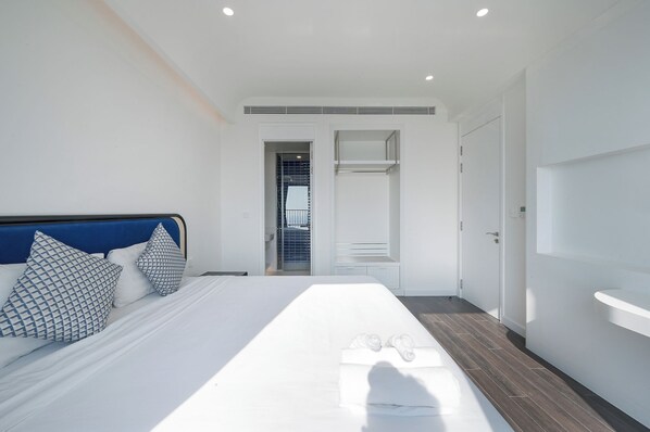 Ein modernes Hotelzimmer mit einem großen Bett, einer blauen Kopfteil und einer weißen Wand.