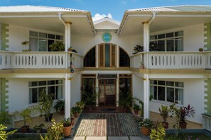 A two-story building with a central entrance, potted plants, and a tiled walkway. - 340 Degrees Mountain View Apartments (Mahé Island)