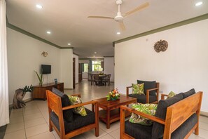 A spacious living area with a ceiling fan, wooden furniture, and a dining table. - 340 Degrees Mountain View Apartments (Mahé Island)