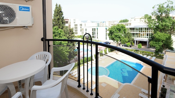 A balcony with a pool view, white plastic chairs, and an air conditioning unit. - Hotel Karlovo Sunny Beach (Nessebar)