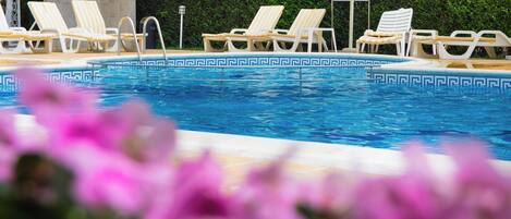 A swimming pool with lounge chairs and a signboard.