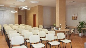 A conference room with rows of chairs, a table with a plant, and a painting on the wall. - Hotel Karlovo Sunny Beach (Nessebar)