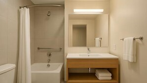 A bathroom with a bathtub, toilet, sink, and mirror. - Saaz Hotel Indore (Indore)
