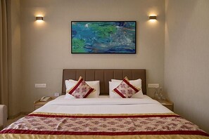 A hotel room with a large bed, two bedside tables, a painting on the wall, and a telephone on one of the tables. - Saaz Hotel Indore (Indore)