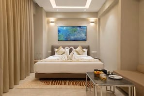 A hotel room with a bed, a painting on the wall, a table with breakfast items, and a sofa. - Saaz Hotel Indore (Indore)