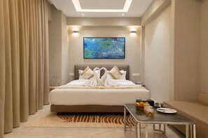 A hotel room with a bed, a painting on the wall, a table with breakfast items, and a sofa. - Saaz Hotel Indore (Indore)