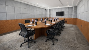 A conference room with a long table, black chairs, and water bottles. - Saaz Hotel Indore (Indore)