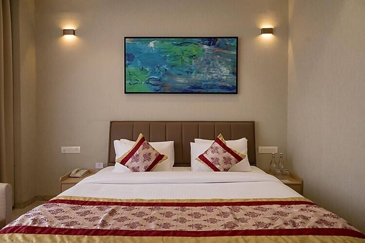 Una habitació d'hotel amb un llit gran, dues taules de nit, un quadre a la paret i un telèfon sobre una de les taules.