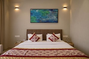 A hotel room with a large bed, two bedside tables, a painting on the wall, and a telephone on one of the tables. - Saaz Hotel Indore (Indore)