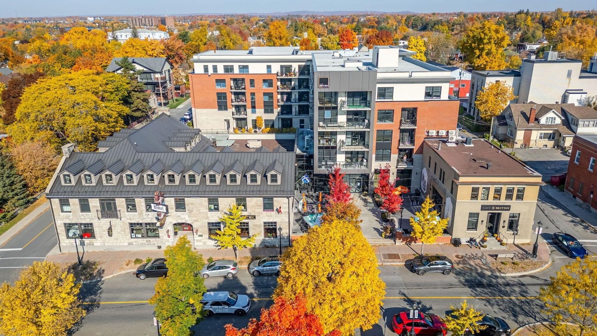 Un hôtel avec une façade en pierre, plusieurs étages et un parking rempli de voitures.