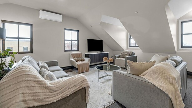Un moderno salón estilo loft con techo alto, televisor empotrado y una zona de estar acogedora.