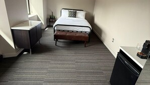 Habitación de hotel moderna con cama, un escritorio pequeño, una silla y un armario empotrado.