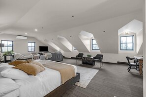 A spacious loft bedroom with a large bed, a desk, and a television.