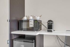 A microwave oven with a digital clock displaying 5:57, a small coffee maker, and a toaster on a white countertop.