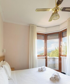 A hotel room with a bed, a ceiling fan, a window with a view, and a door. - Hotiday Bordighera (Bordighera)