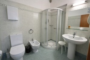 A bathroom with a toilet, bidet, glass-enclosed shower, sink, and mirror. - Hotiday Bordighera (Bordighera)
