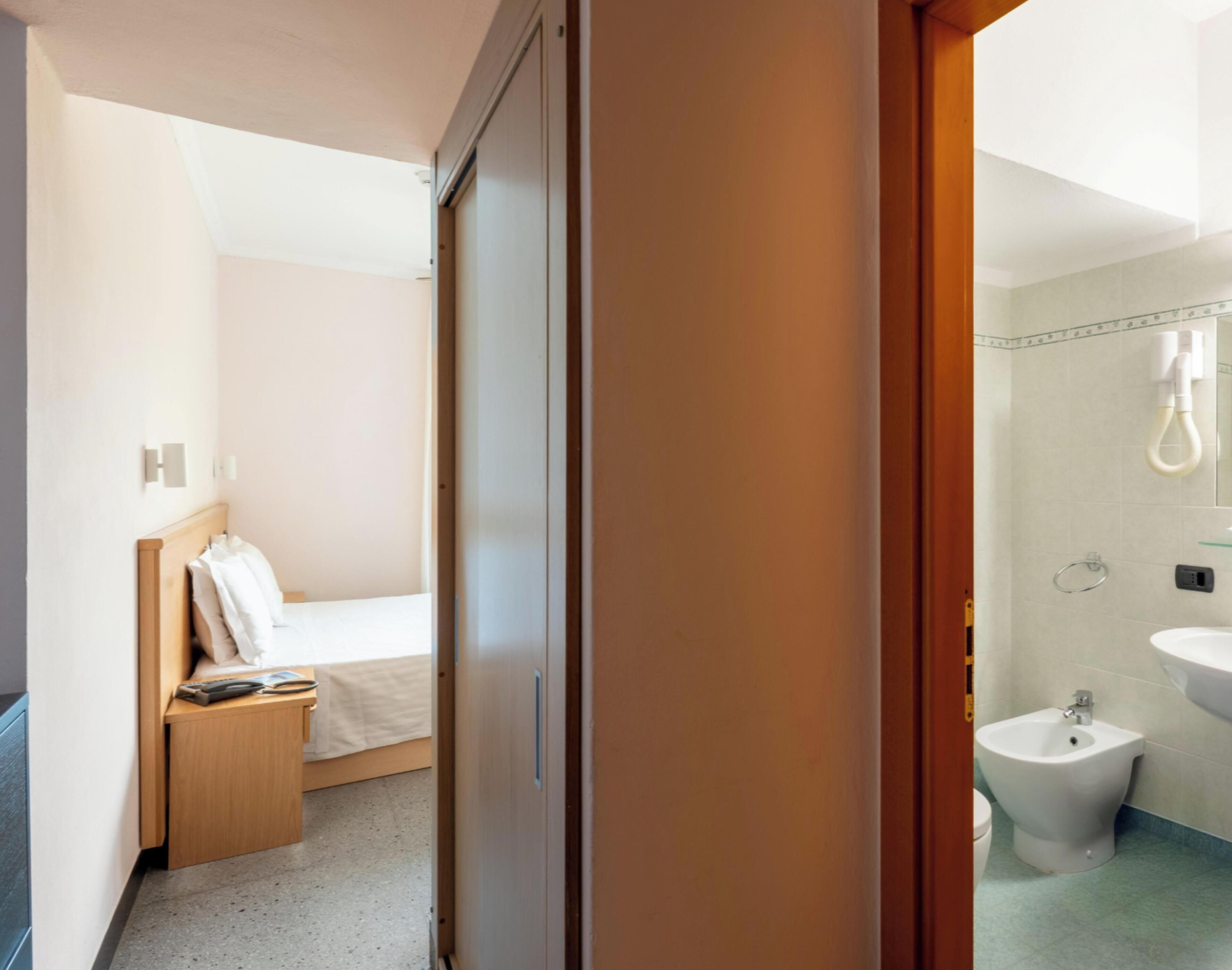 Ein Hotelzimmer mit Bett, Nachttisch und einem Badezimmer mit Bidet und Waschbecken.