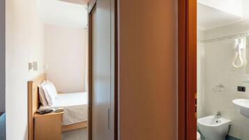 Ein Hotelzimmer mit Bett, Nachttisch und einem Badezimmer mit Bidet und Waschbecken.