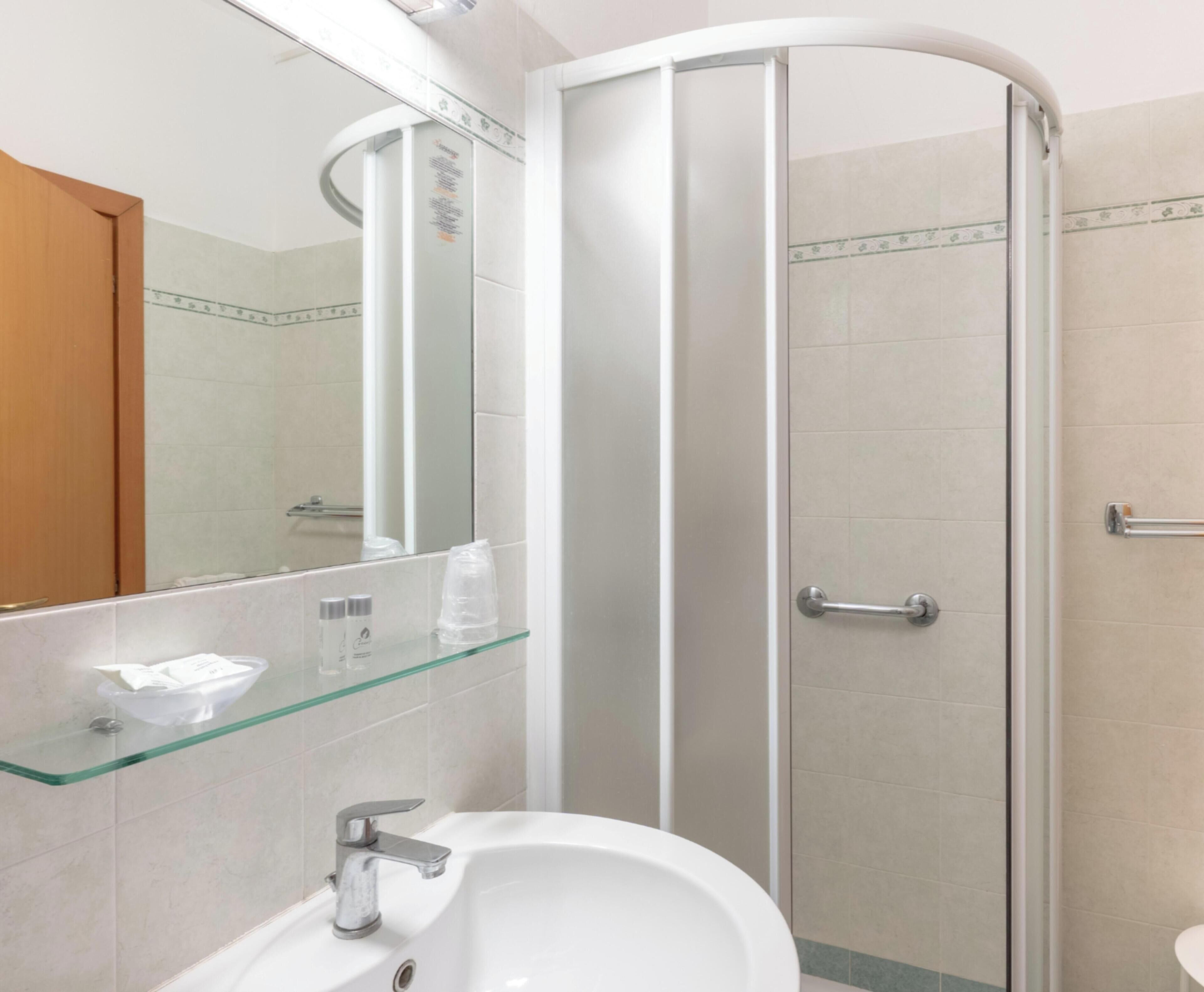 Un baño moderno con cabina de ducha de vidrio, un lavabo blanco y un espejo sobre él.