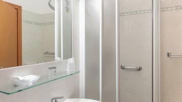 Un baño moderno con cabina de ducha de vidrio, un lavabo blanco y un espejo sobre él.