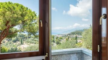 Una habitación con vista a un árbol y un paisaje lejano a través de una ventana.
