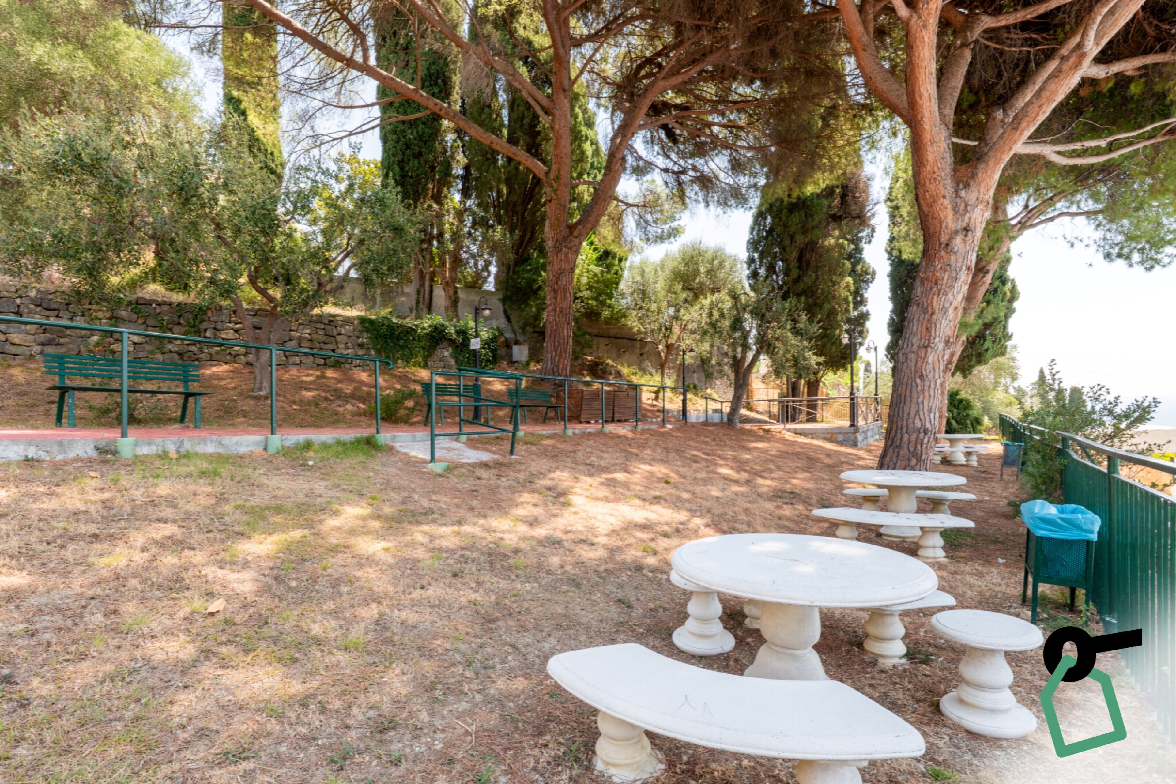 Un parc doté d’un espace extérieur aménagé avec des sièges, des murs en pierre et des arbres.