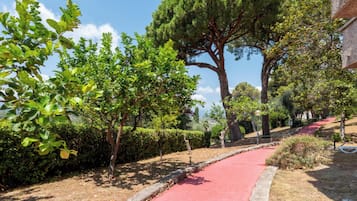 Un sendero bordeado de árboles y un camino rojo que conduce a un edificio de fachada de piedra.