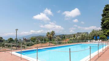 Una piscina rectangular con cielo azul despejado y montañas lejanas al fondo.