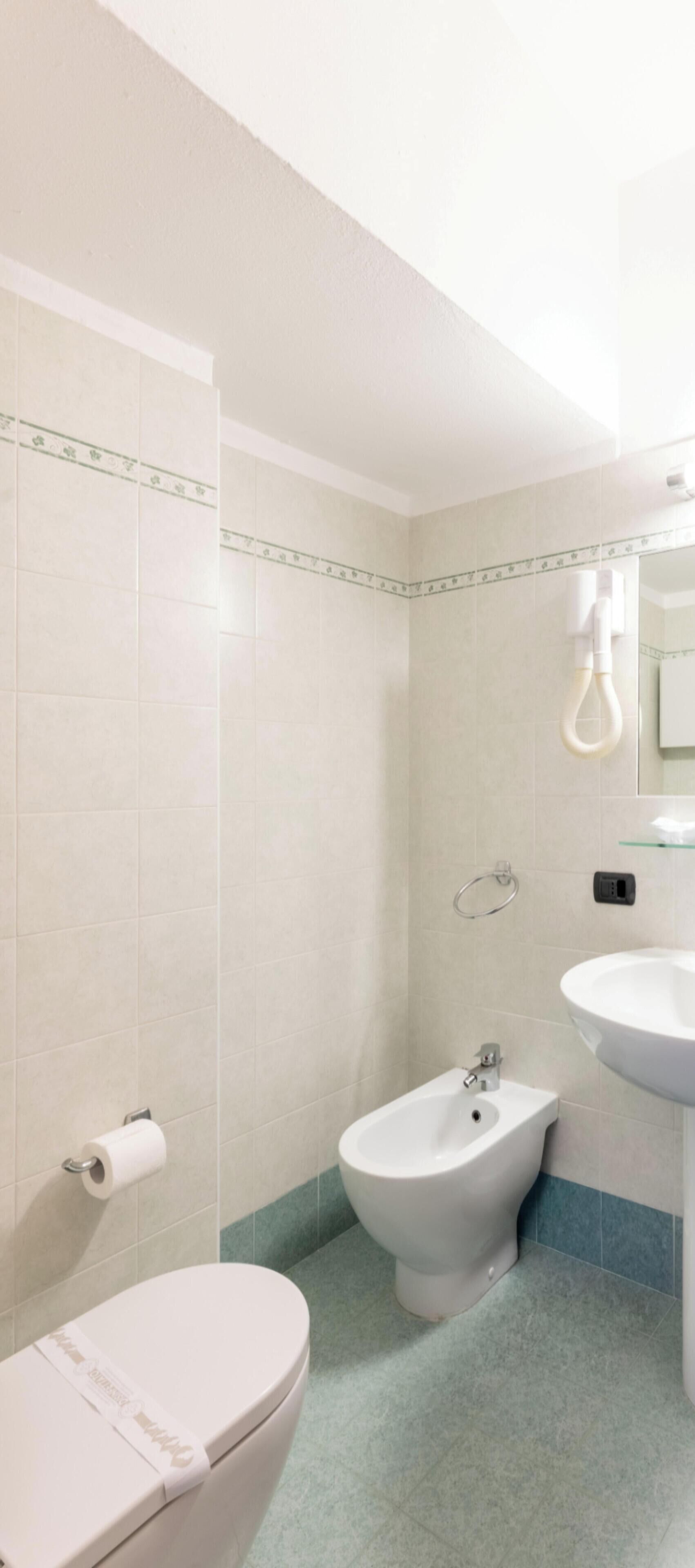Un baño con inodoro, bidé y lavamanos.