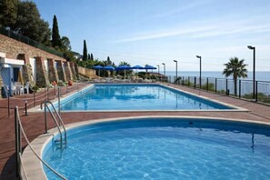 A rectangular swimming pool with a clear blue water surface, surrounded by a brick wall with a metal railing.