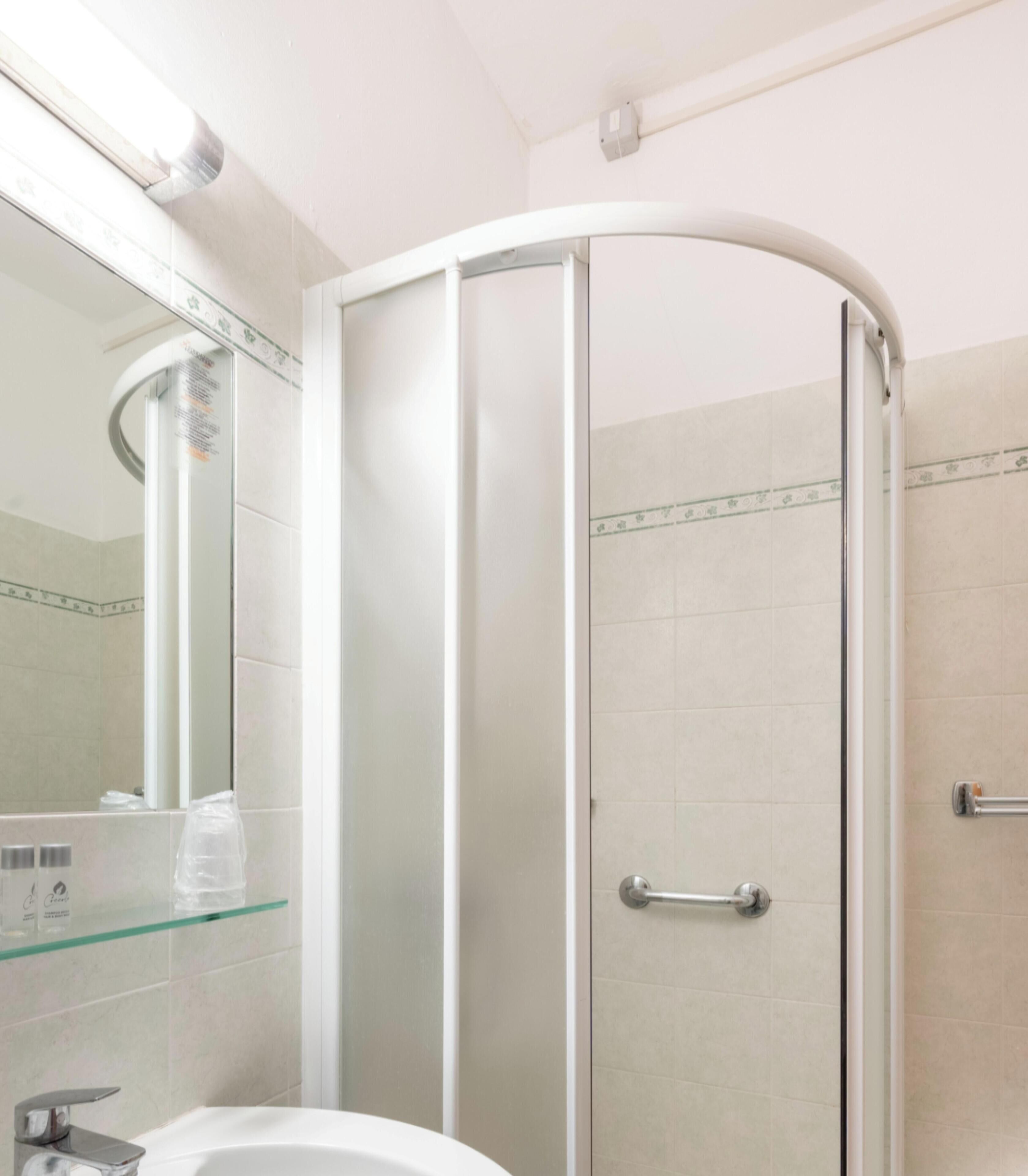 Un baño con cabina de ducha de vidrio, un lavabo y un espejo.