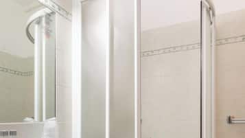 Un baño con cabina de ducha de vidrio, un lavabo y un espejo.