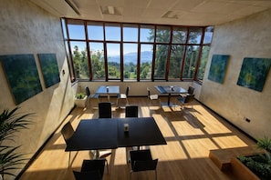 Une salle de conférence dotée de grandes fenêtres, de plusieurs tables, de chaises et d’œuvres d’art accrochées aux murs.