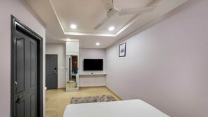 Ein modernes Schlafzimmer mit Bett, Deckenventilator, Einbauleuchten, Fernseher und Spiegel.