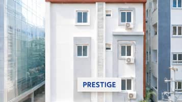 Un edificio de varios pisos con un llamativo letrero 'PRESTIGE', unidades de aire acondicionado y fachada de vidrio.