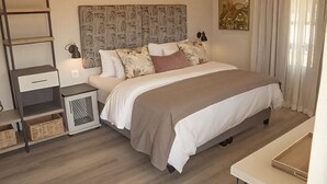 A bedroom with a bed, bedside tables, a headboard, a nightstand, a wall art piece, and a window with curtains. - Vyge Valley Estate (Cape Town)